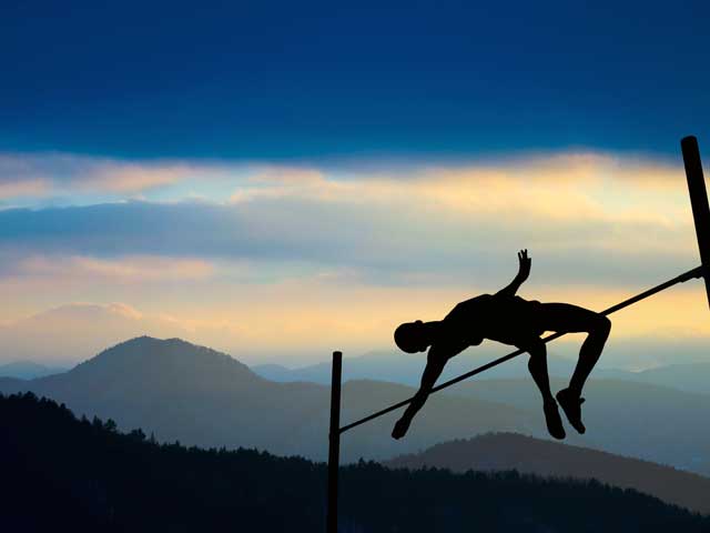 Silhouette of athlete competing in pole vault at dusk